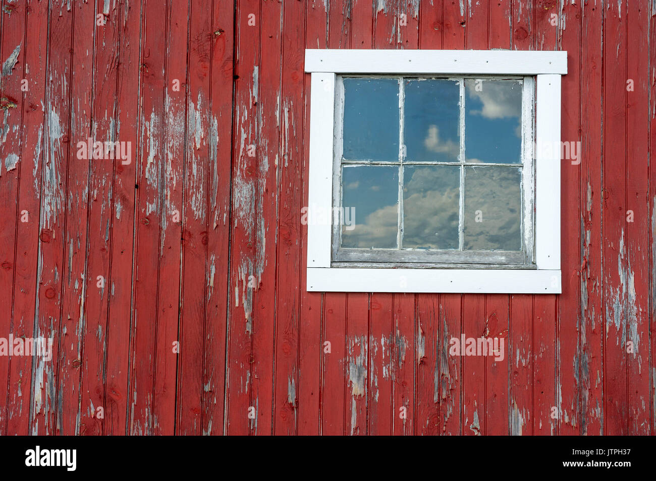 Sky reflects in window on worn-down red barn in Harford County, Maryland. Stock Photo