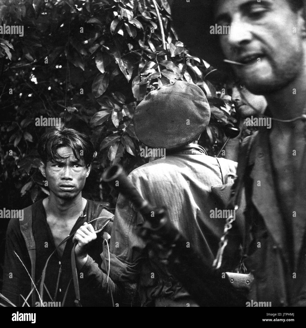 The French Foreign Legion is playing the major combat role in the war against the Vietminh.  Here a red-suspect has been found hiding in the jungle and is now being questioned by the advance patrol, who caught him.  Ca.  1954.  Pix.  (USIA) EXACT DATE SHOT UNKNOWN NARA FILE #:  306-PS-55-10516 WAR & CONFLICT BOOK #:  383 Stock Photo