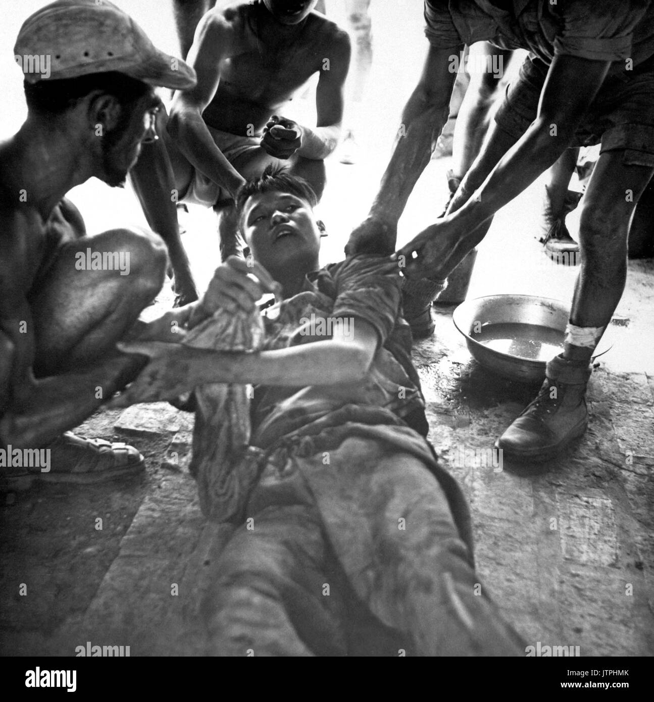 A wounded Vietminh prisoner is given first aid by Franco Vietnamese medicals after hot fire fight near Hung Yen, south of Hanoi.  Ca.  1954  (USIA) EXACT DATE SHOT UNKNOWN NARA FILE #:  306-PS-54-11793 WAR & CONFLICT BOOK #:  384 Stock Photo