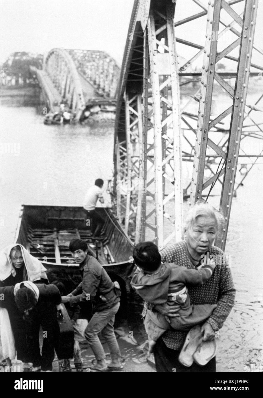 The old and the young flee Tet offensive fighting in Hue, managing to reach the south shore of the Perfume River despite this blown bridge.  1968. (USIA) EXACT DATE SHOT UNKNOWN NARA FILE #:  306-MVP-22-9 WAR & CONFLICT BOOK #:  406 Stock Photo