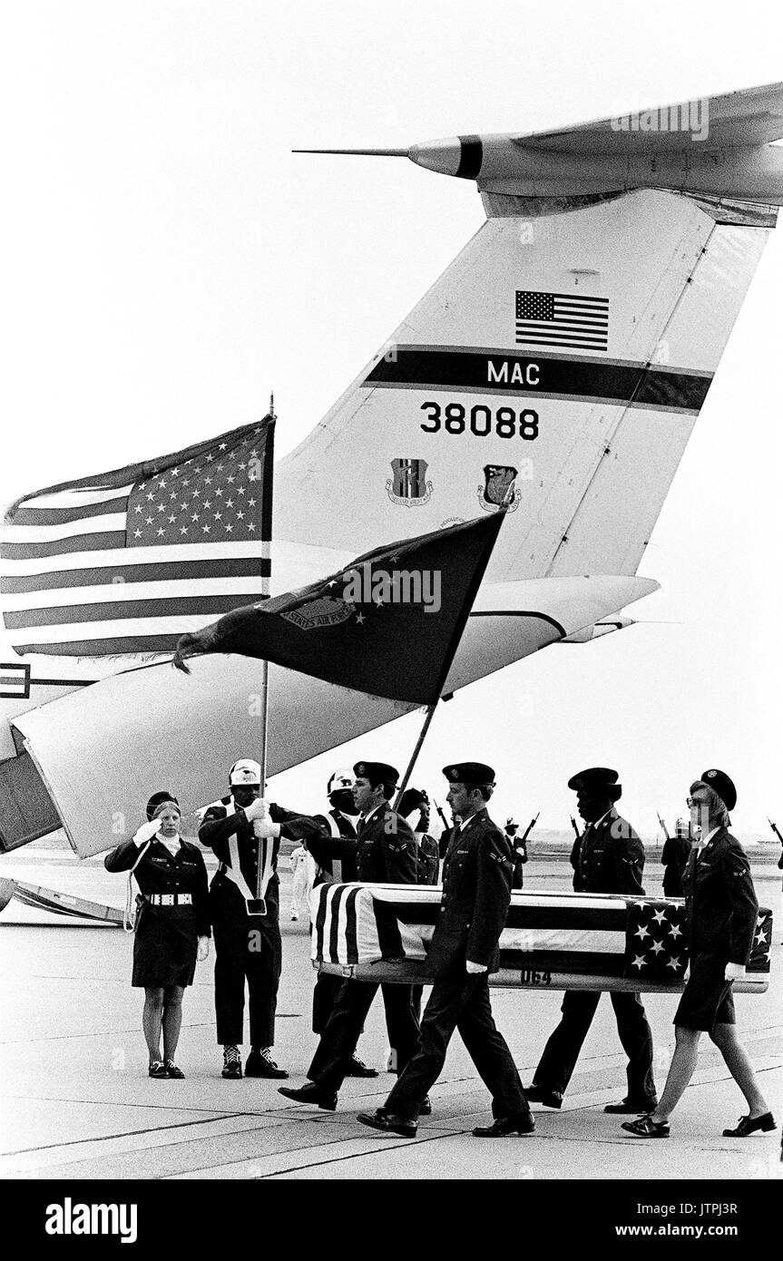 An Air Force honor guard stands at attention while pallbearers carry the transfer case of an MIA away from a C-141 Starlifter aircraft.  The C-141 transported the remains of POW's and MIA's from North Vietnam. Stock Photo