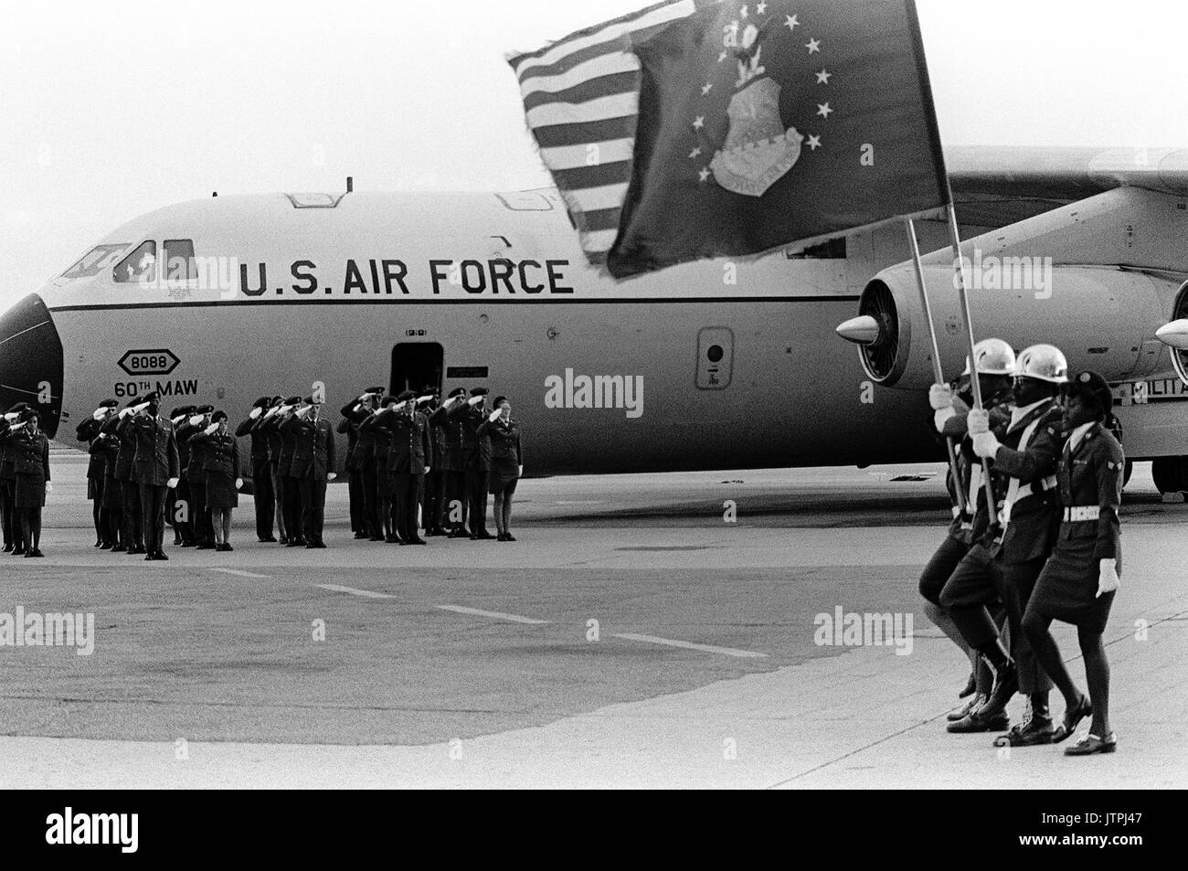An Air Force honor guard salutes the flags as they are paraded alongside a C-141 Starlifter that transported the remains of POW's and MIA's from North Vietnam. Stock Photo