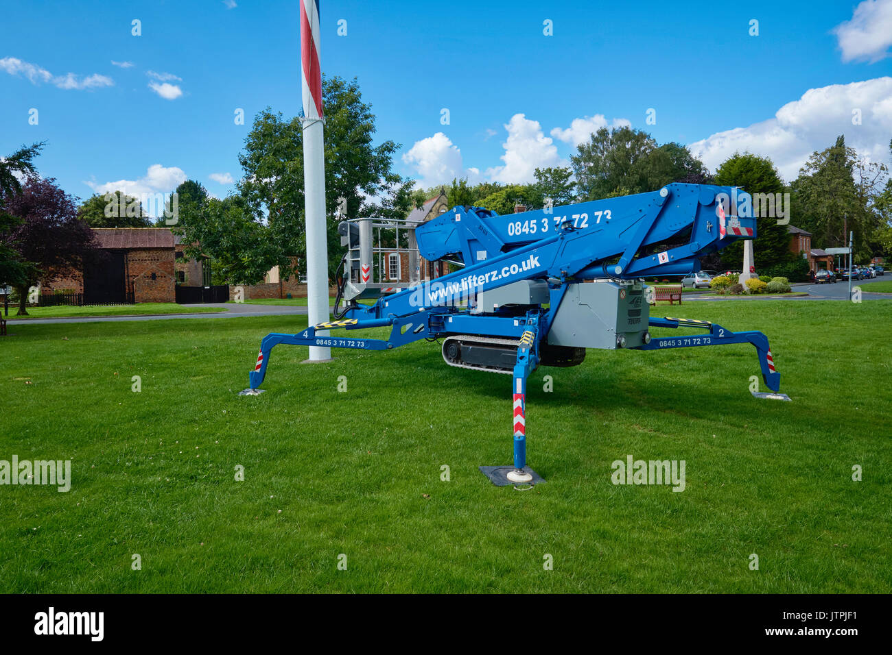 Blue mobile elevating work platform (MEWP) at the foot of a village Maypole for maintenance purposes. Stock Photo