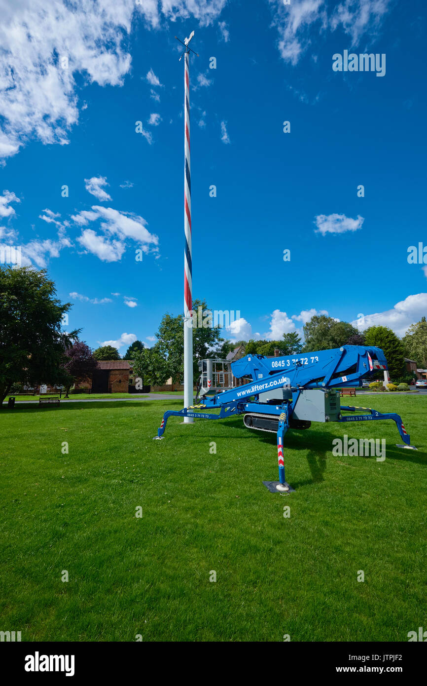 Blue mobile elevating work platform (MEWP) at the foot of a village Maypole for maintenance purposes. Stock Photo