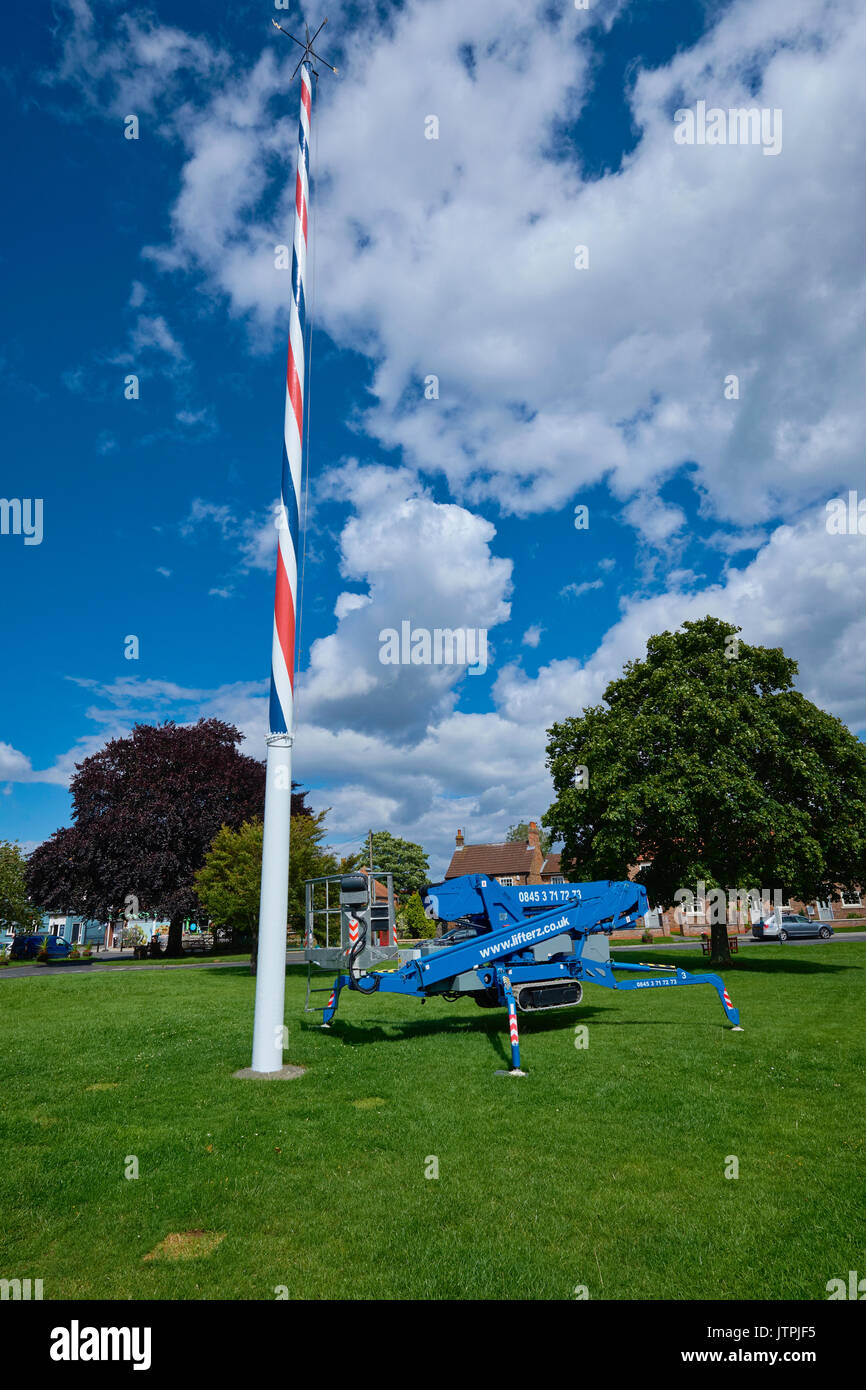 Blue mobile elevating work platform (MEWP) at the foot of a village Maypole for maintenance purposes. Stock Photo