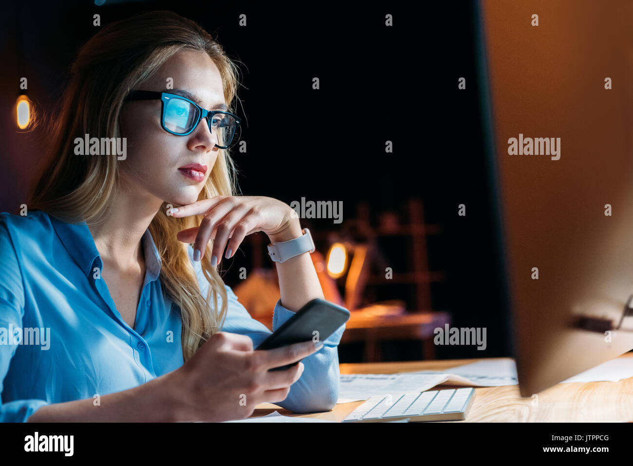 portrait of businesswoman using smartphone while working late in office Stock Photo