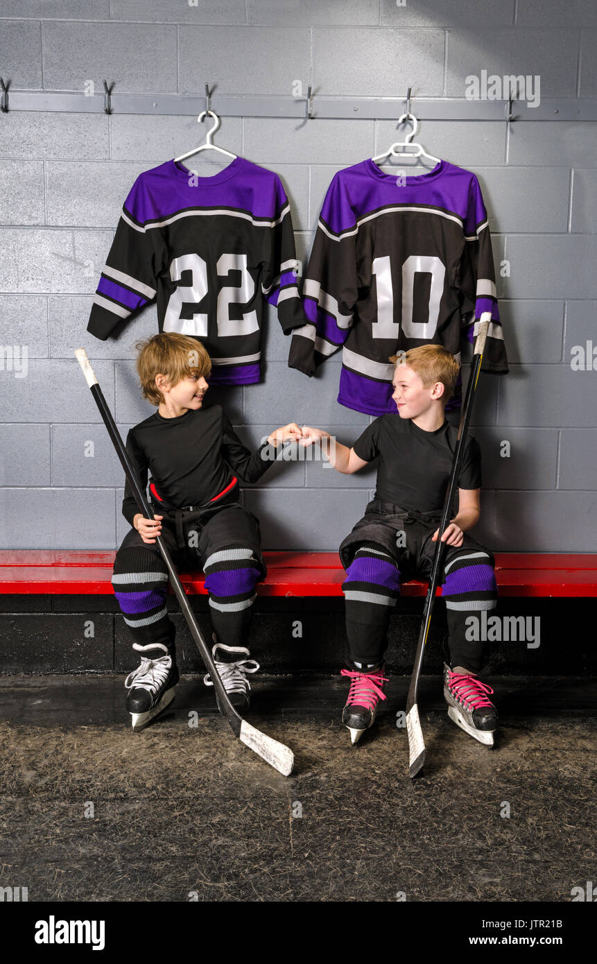 Two young boys fist pump before hockey game in dressing room Stock