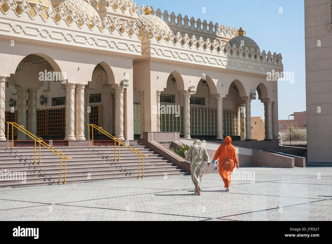Two muslim women in traditional dress going to an large ornate mosque for prayer Stock Photo