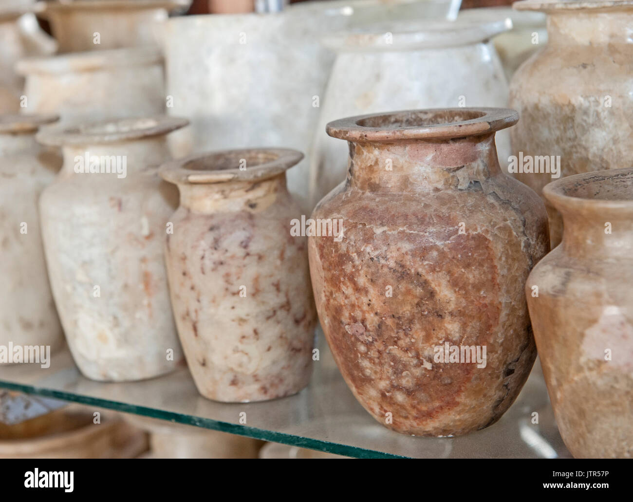 Row of hand crafted alabaster jars and vases on glass shelf at an egyptian market shop stall Stock Photo