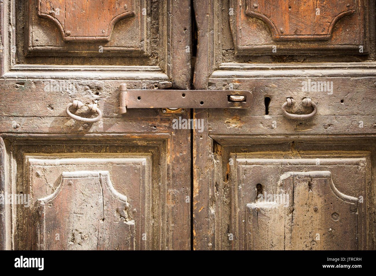 Old rusty latch close up on an ancient wooden door with metal handles. Stock Photo