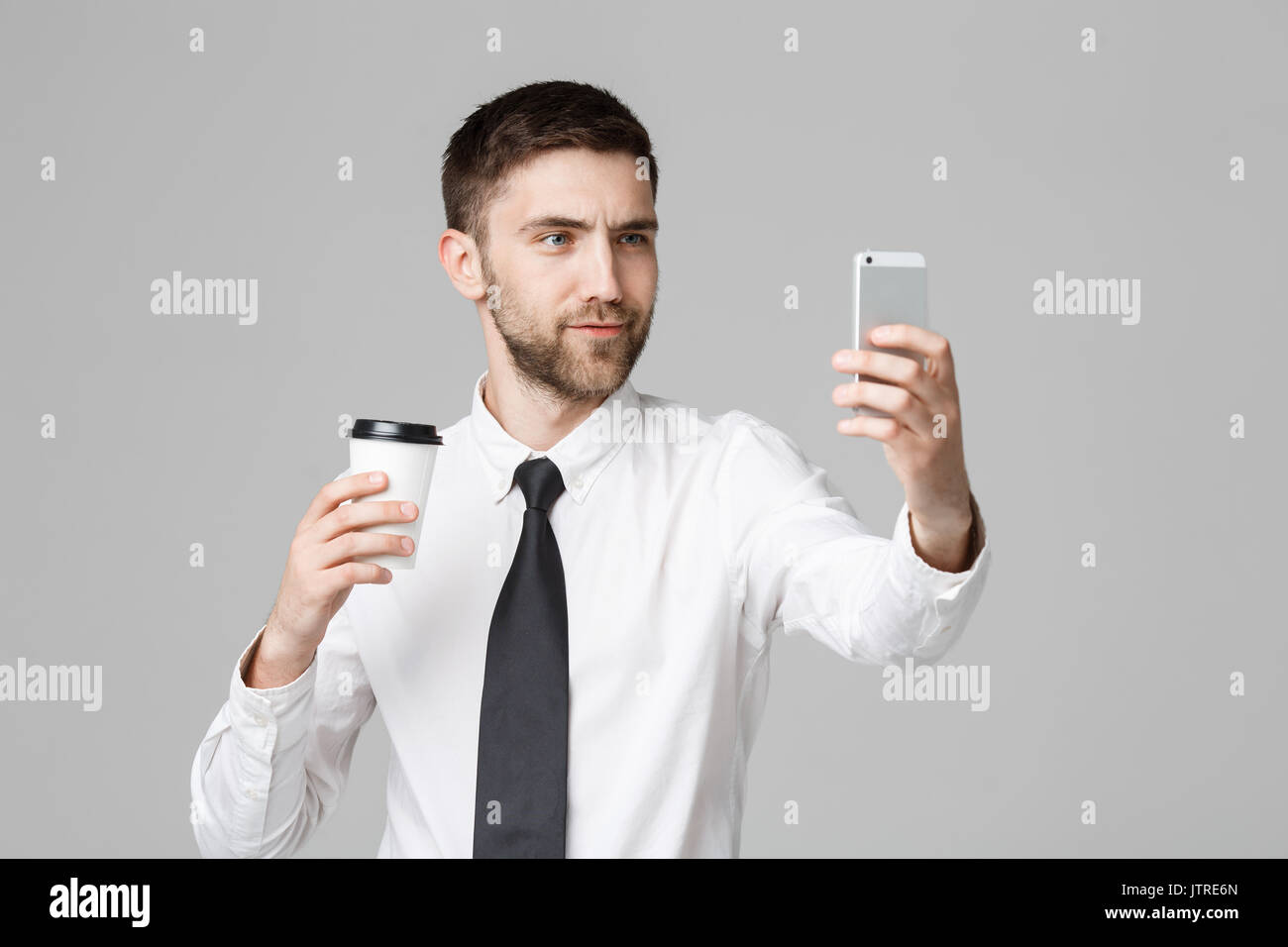 Lifestyle and Business Concept - Portrait of a handsome businessman enjoy taking a selfie with take away cup of coffee. Isolated White background. Cop Stock Photo