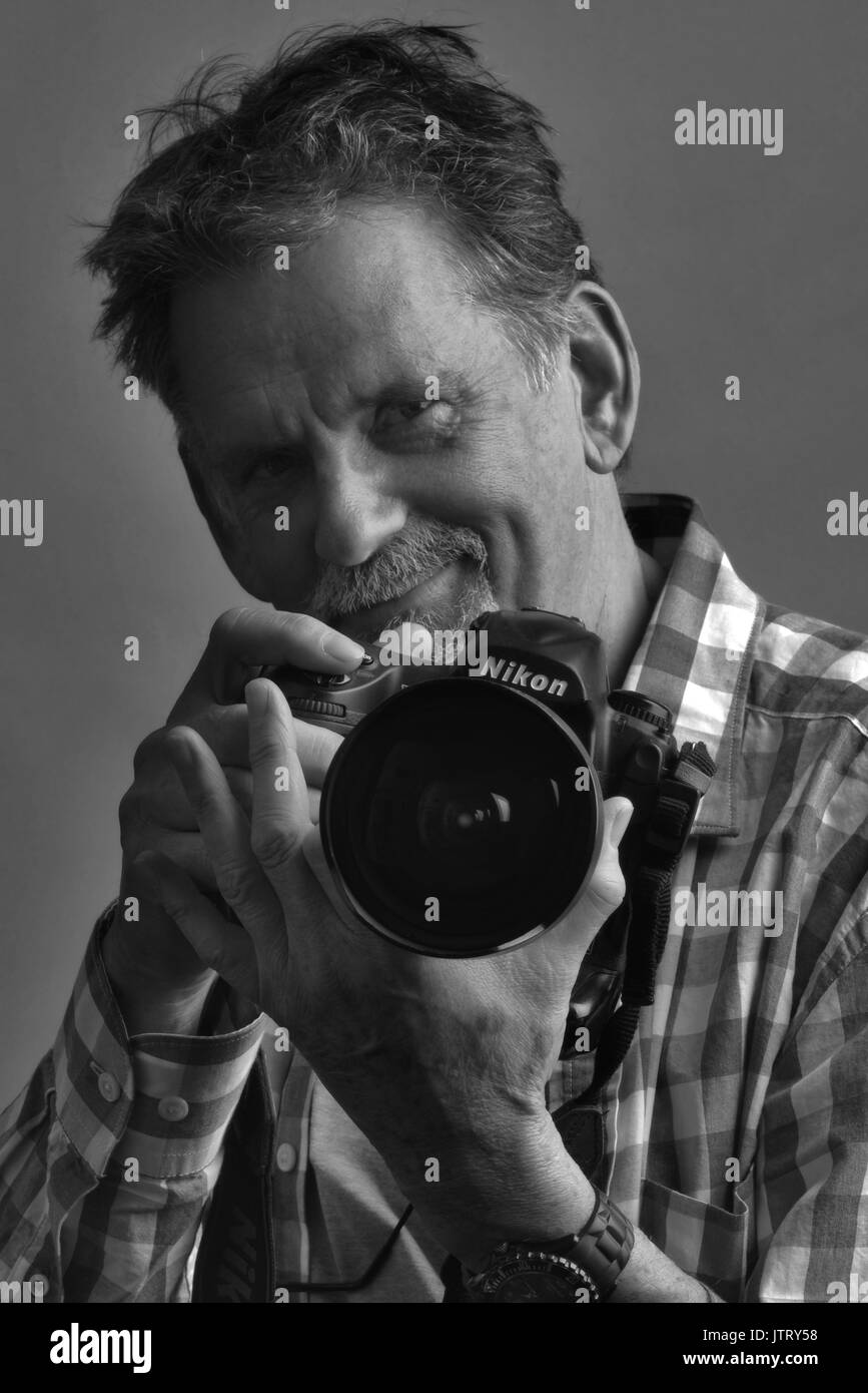 Black and white, self portrait of photographer Jon Davison, holding a Nikon camera. Stock Photo