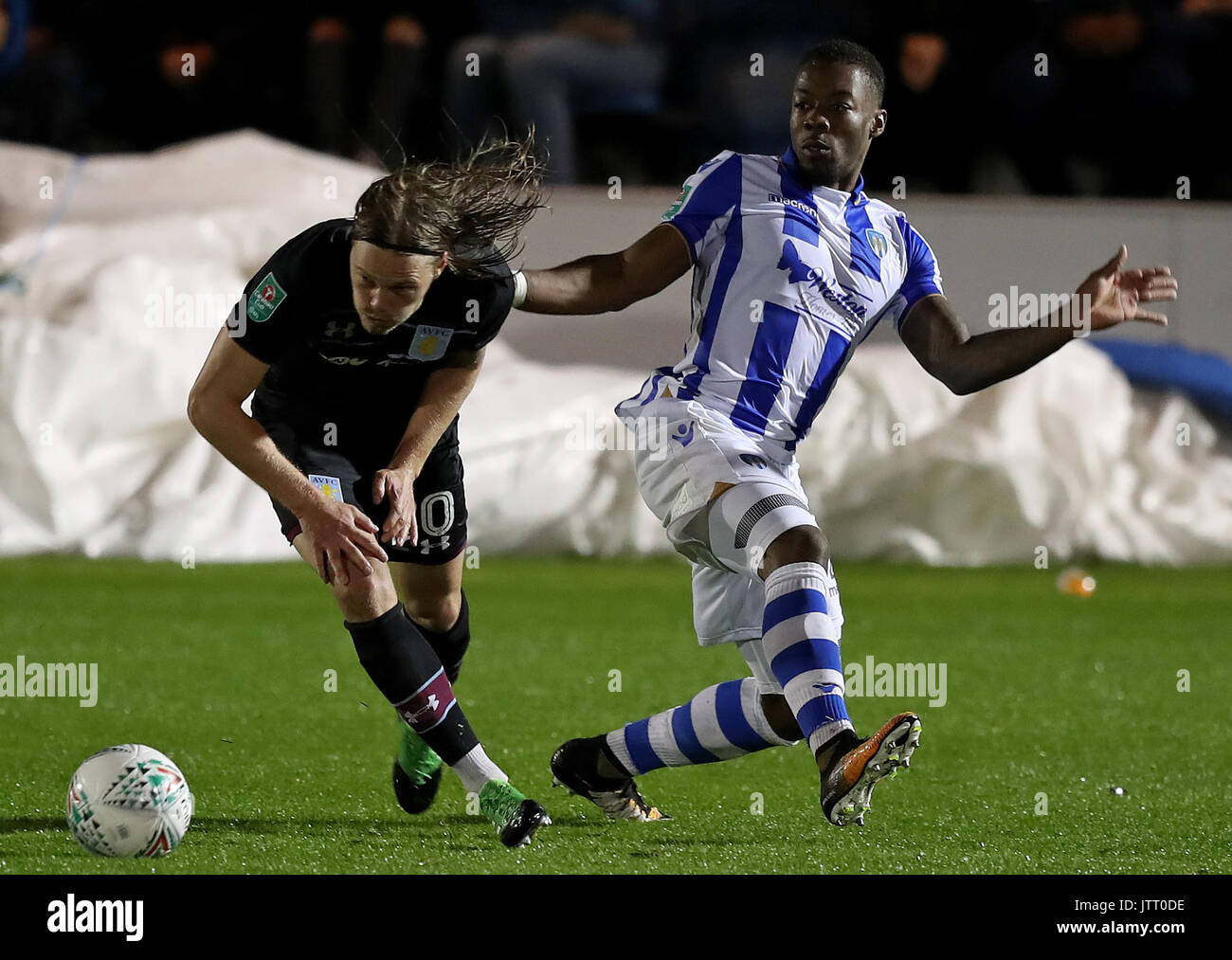 Aston Villa's Birkir Bjarnason (left) and Colchester United's Ryan Jackson battle for the ball during the Carabao Cup, First Round match at the Weston Homes Community Stadium, Colchester. Stock Photo