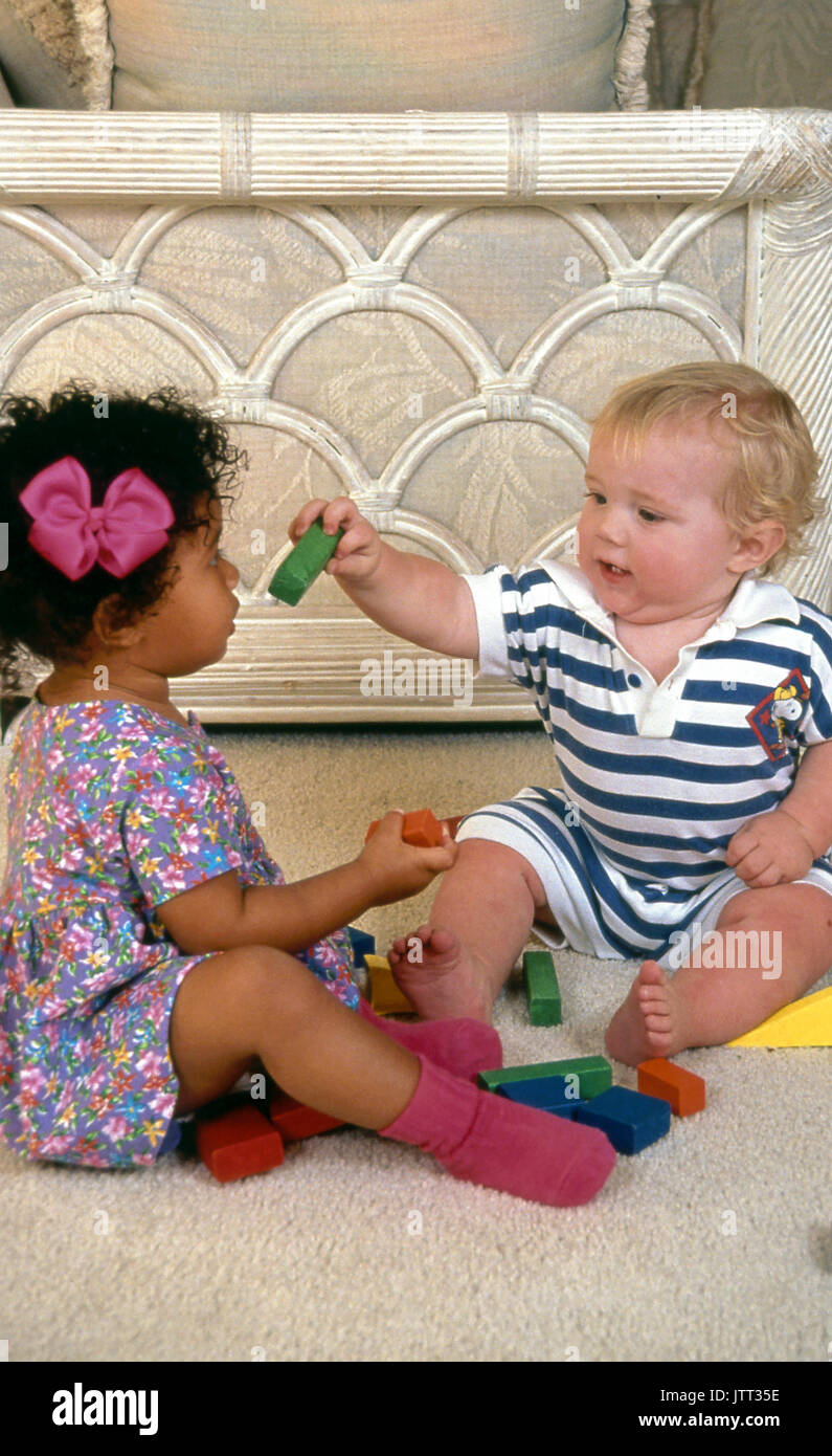young caucasian baby sharing gives toy block to African American 2 year old girl 18 month old boy © Myrleen Pearson Stock Photo