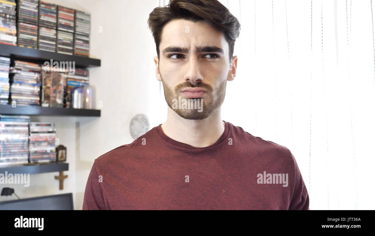 Confused or doubtful young man looking up Stock Photo