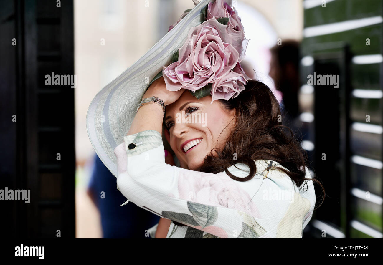 Brighton, UK. 10th Aug, 2017. Maria Cheslin makes adjustments to her hat on a bright but breezy day at Brighton Races Route Mobile Ladies Day during the three day Maronthonbet Festival of Racing Credit: Simon Dack/Alamy Live News Stock Photo