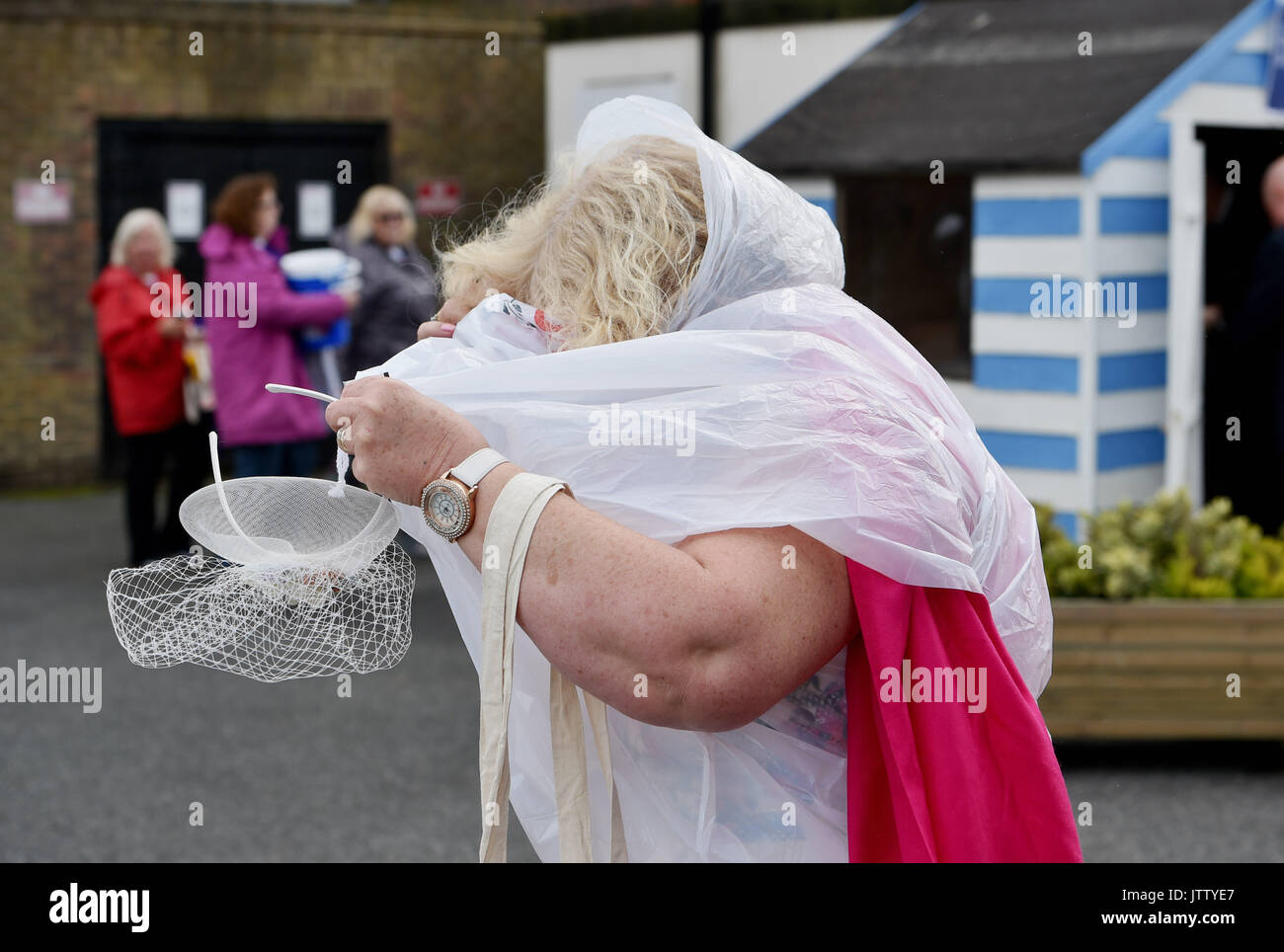 Brighton, UK. 10th Aug, 2017. This lady has trouble with her ponch on a bright but breezy day at Brighton Races Route Mobile Ladies Day during the three day Maronthonbet Festival of Racing Credit: Simon Dack/Alamy Live News Stock Photo