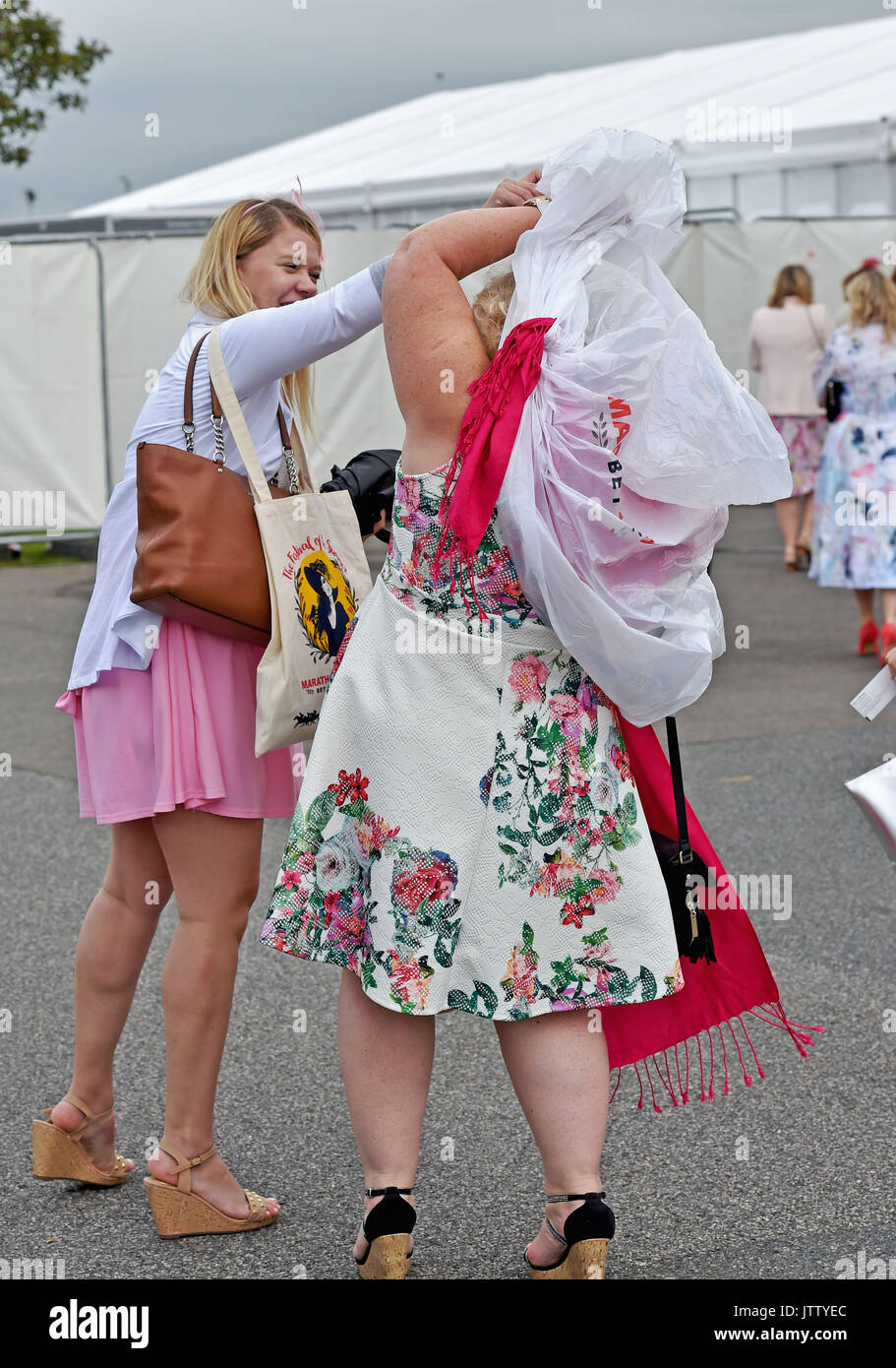 Brighton, UK. 10th Aug, 2017. This lady has trouble with her ponch on a bright but breezy day at Brighton Races Route Mobile Ladies Day during the three day Maronthonbet Festival of Racing Credit: Simon Dack/Alamy Live News Stock Photo