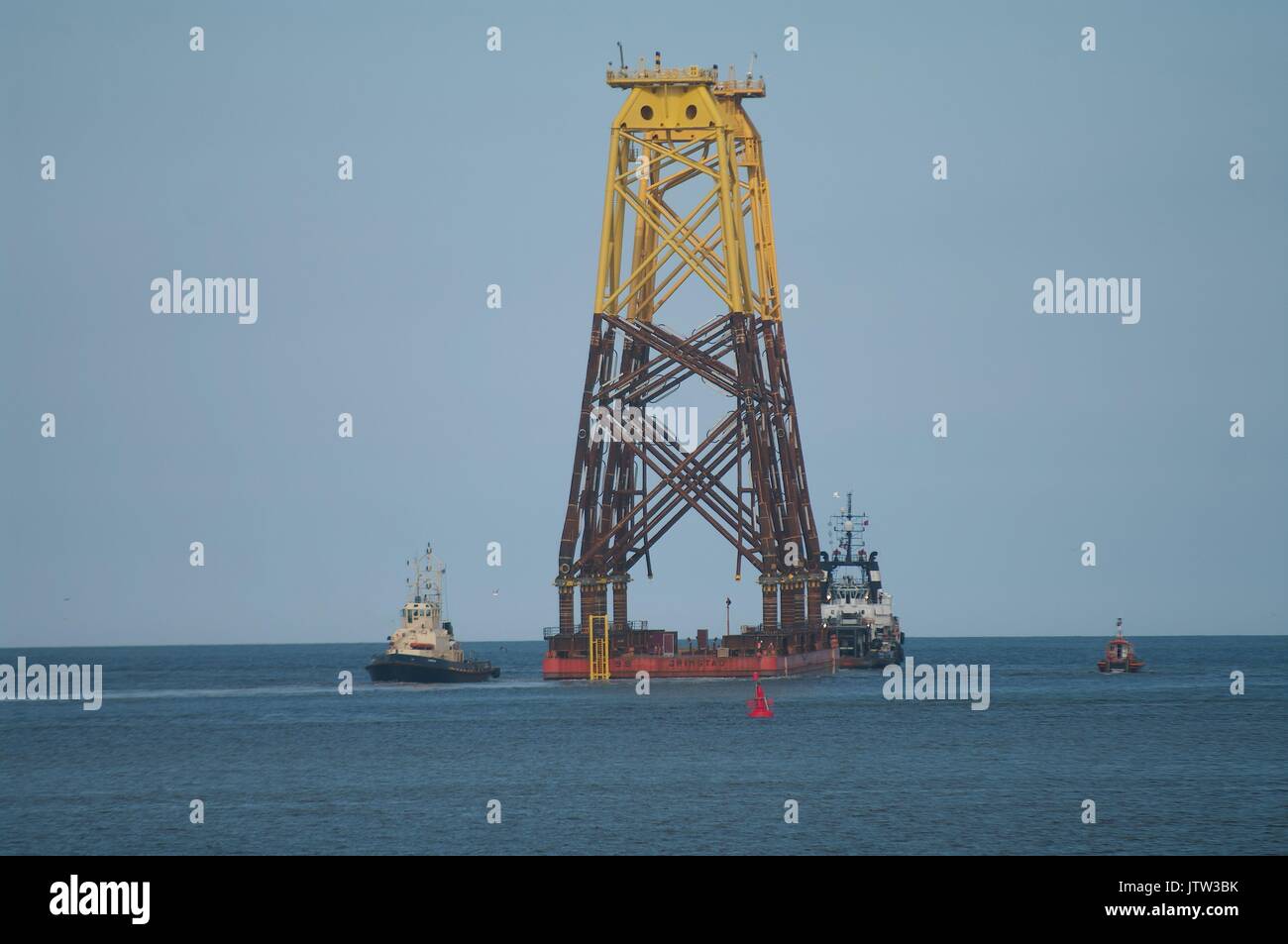 River Tyne, South Shields, UK, 10th August 2017. Wind turbine foundations at the mouth of the River Tyne on their way to the Beatrice offshore wind farm in the Moray Firth. Due to their height National Grid had to raise the height of power cables across the River Tyne despite the pylons being two of the highest in Britain, surpassed only by sets spanning the River Thames near London and the River Severn in Bristol. Credit: Colin Edwards/Alamy Live News. Stock Photo