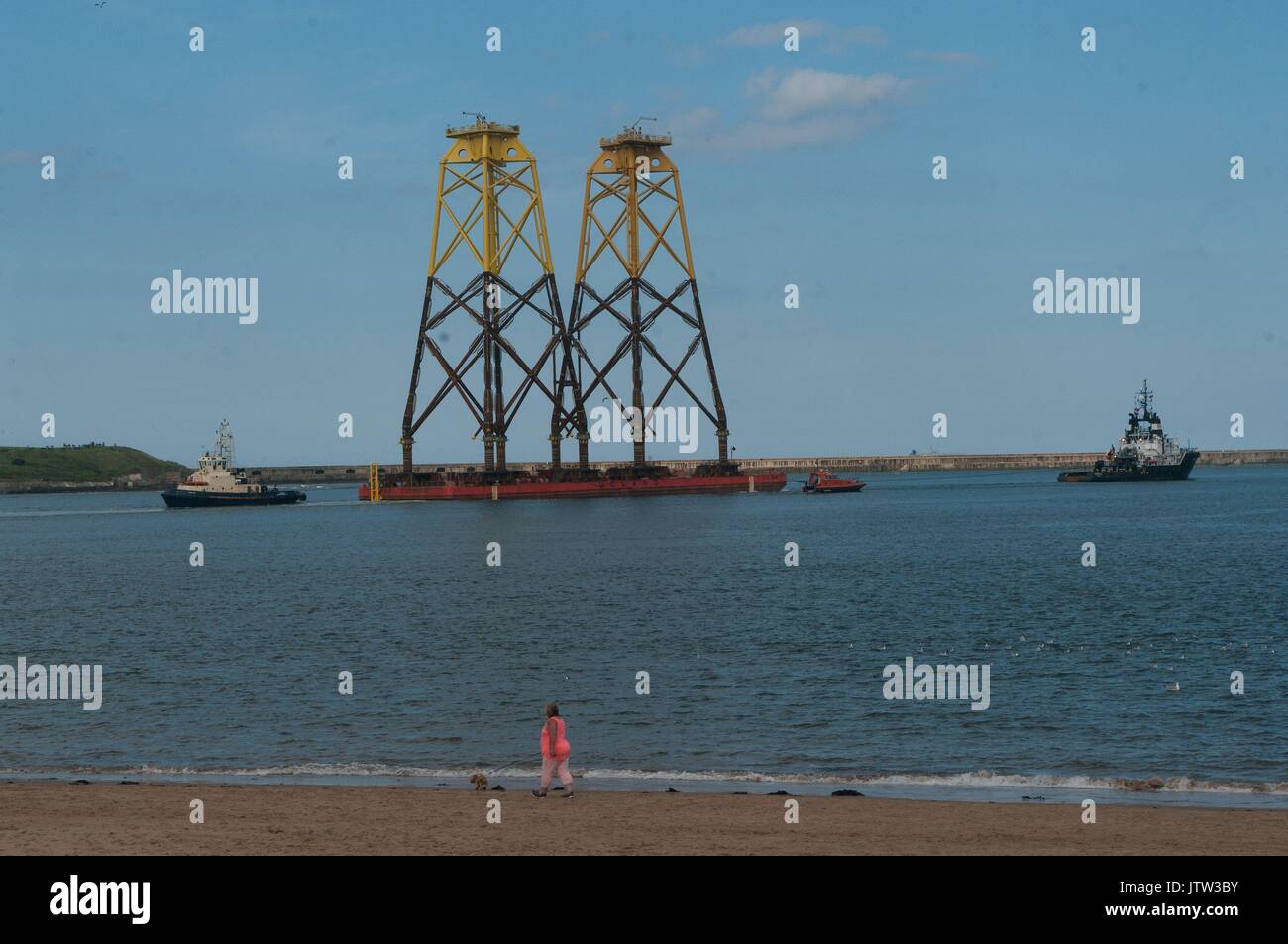 River Tyne, South Shields, UK, 10th August 2017. Wind turbine foundations being towed at the mouth of the River Tyne on their way to the Beatrice offshore wind farm in the Moray Firth. Due to their height National Grid had to raise the height of power cables across the River Tyne despite the pylons being two of the highest in Britain, surpassed only by sets spanning the River Thames near London and the River Severn in Bristol. Credit: Colin Edwards/Alamy Live News. Stock Photo