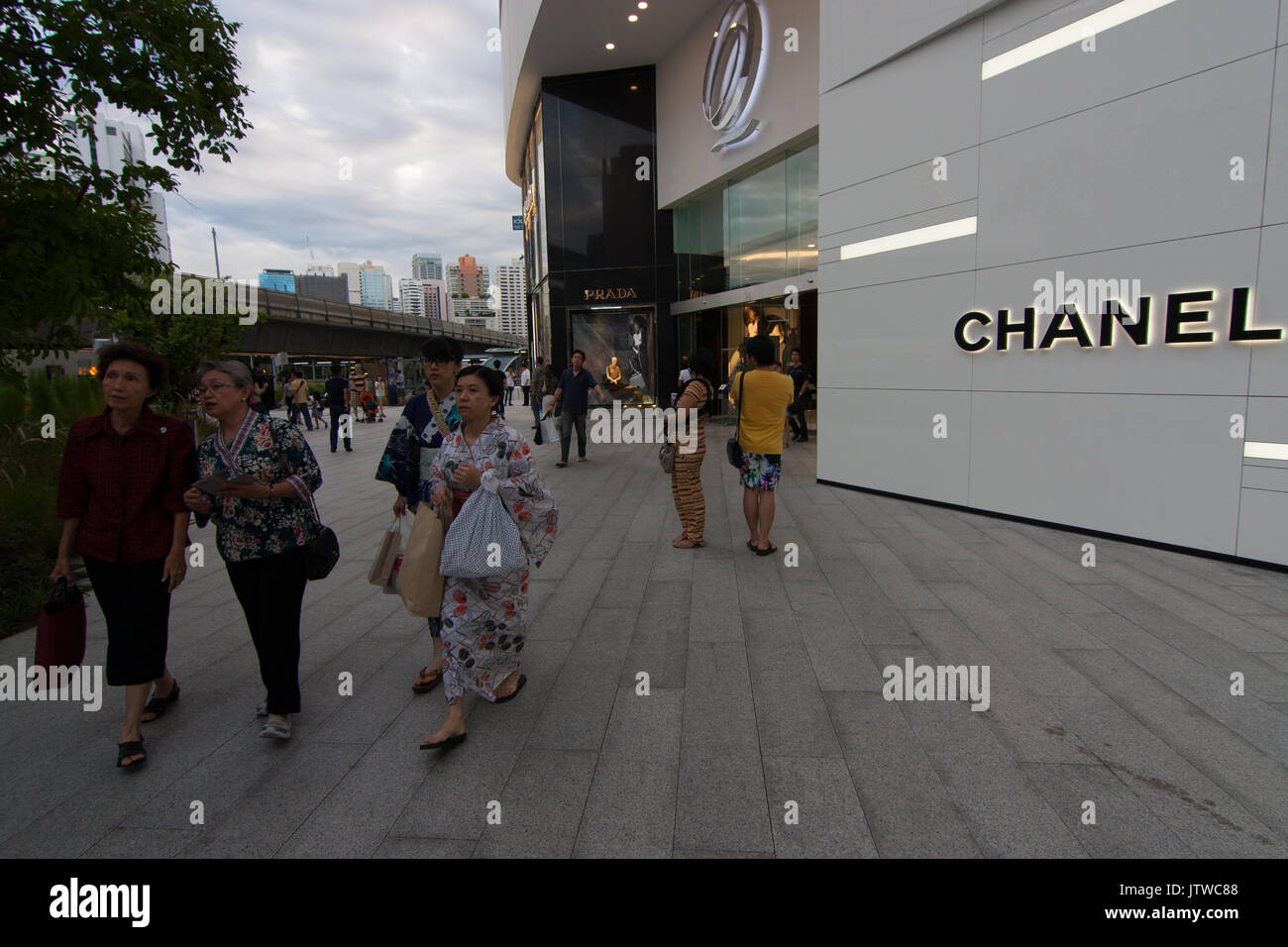 At the luxury mall Emquartier, two Japanese ladies in Yukata walk alongside two senior Thai ladies in front of a Chanel shop. Stock Photo