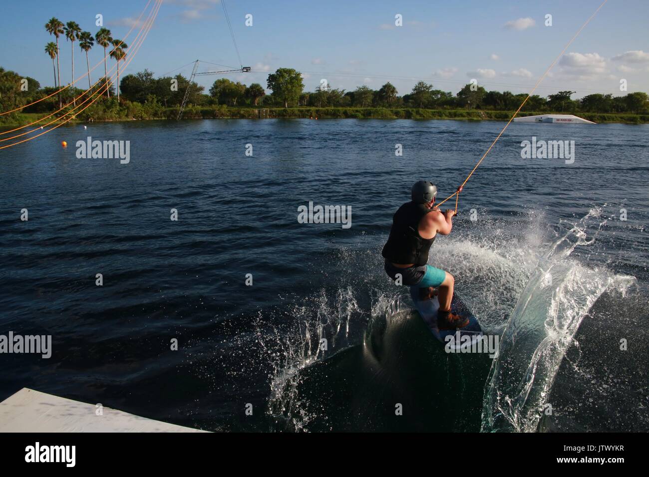 Young Woman Being Launched Pulled by Cable on Wakeboard into Lake Stock Photo