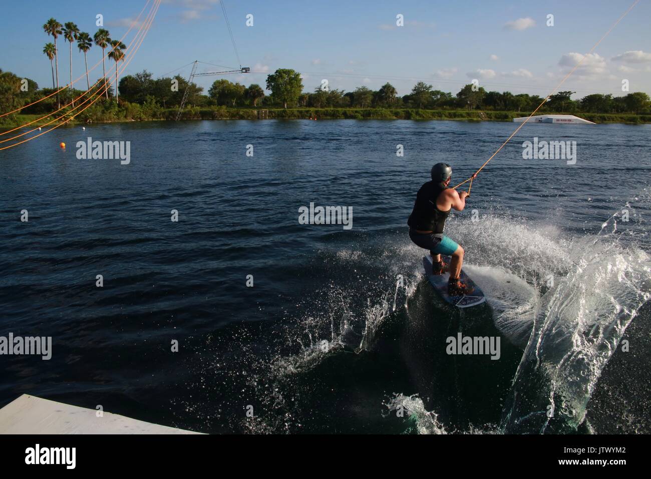 Young Woman Being Launched Pulled by Cable on Wakeboard into Lake Stock Photo