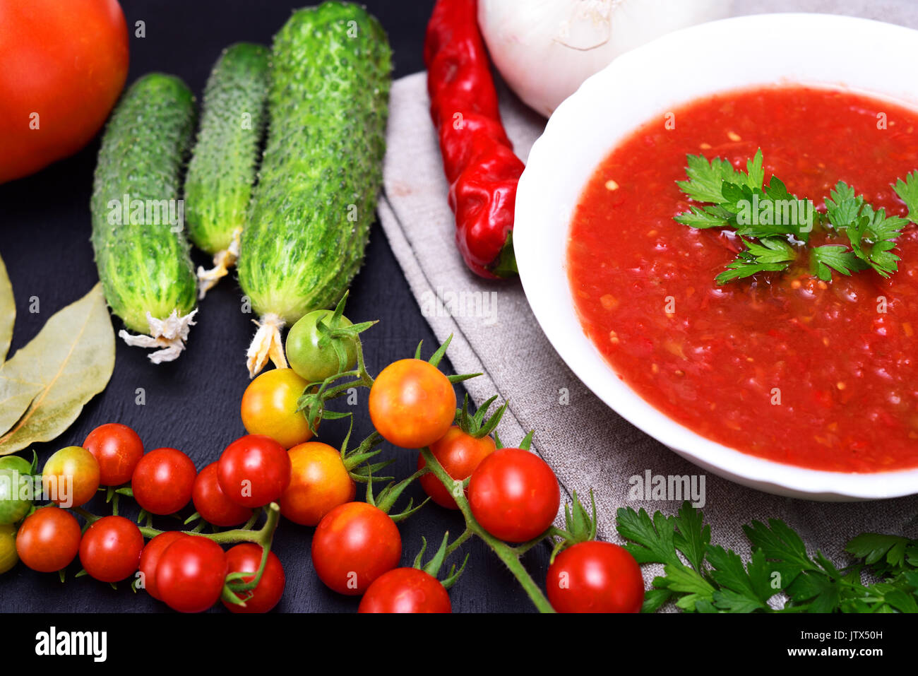 Cold summer soup gazpacho from fresh vegetables in a round white ceramic plate, top view Stock Photo