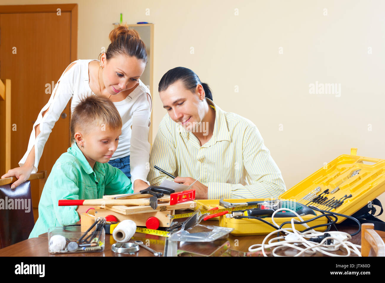 Ordinary family of three doing something with the working tools at home Stock Photo