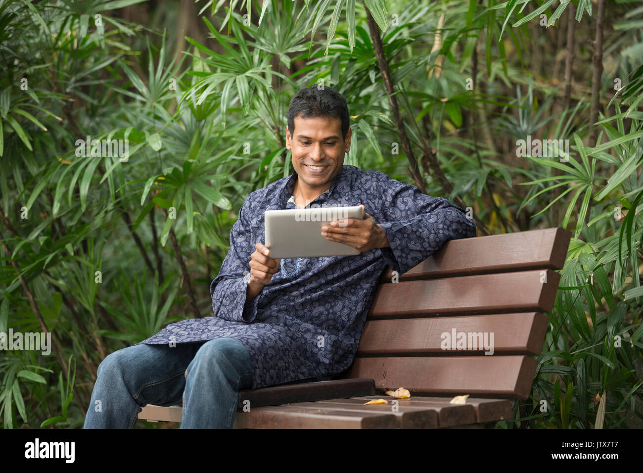 Happy Indian man using tablet computer on street. Traditional indian ...