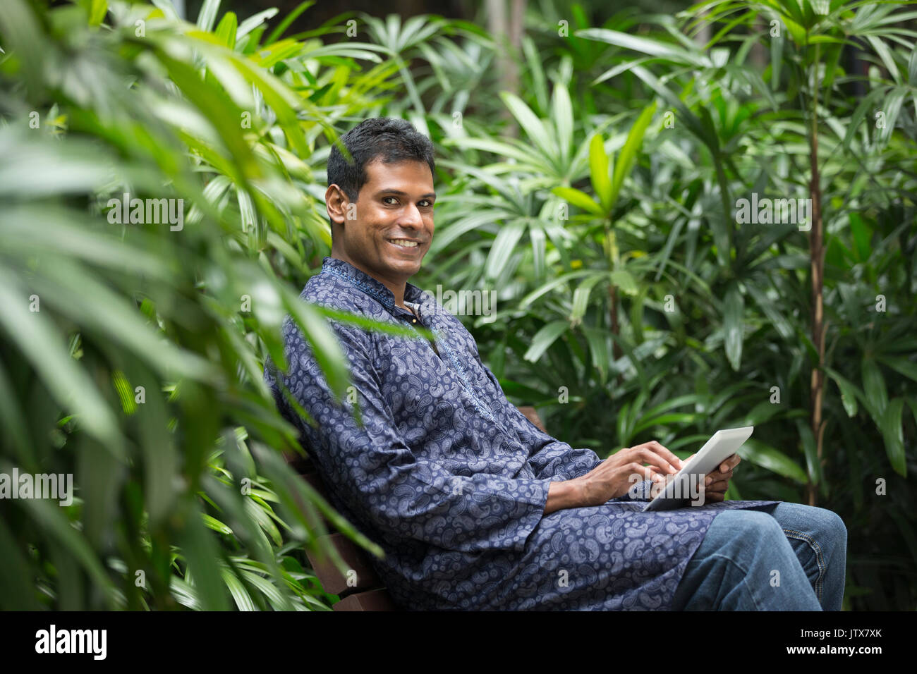Happy Indian man using tablet computer on street. Traditional indian ...