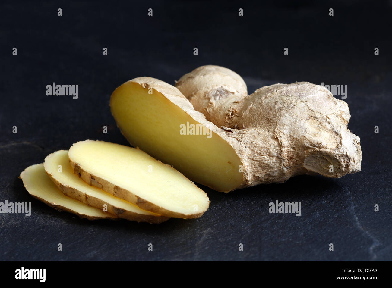 Sliced ginger root isolated on black slate. Stock Photo