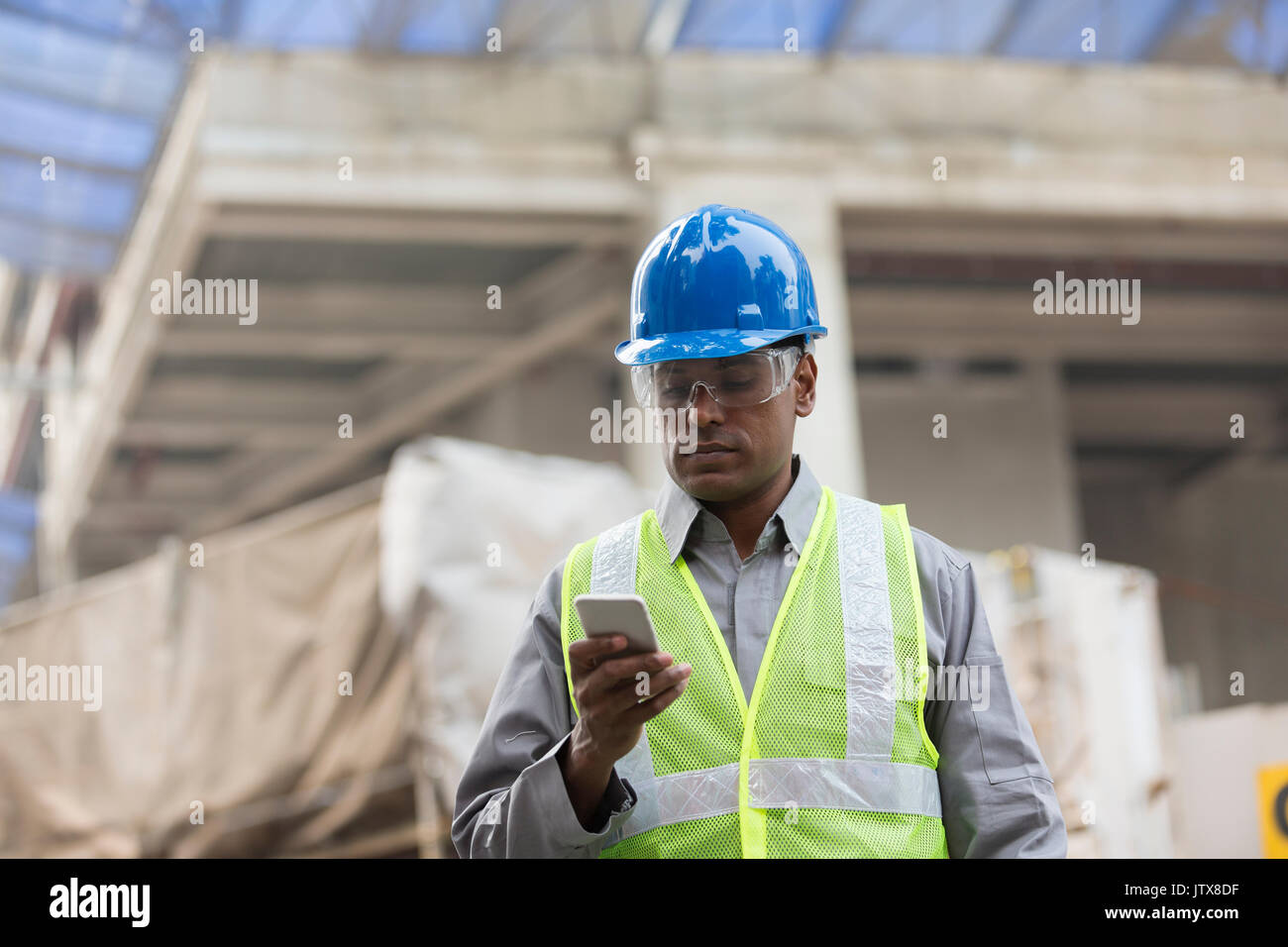 Portrait of a male Indian builder or industrial engineer at work using phone. Stock Photo