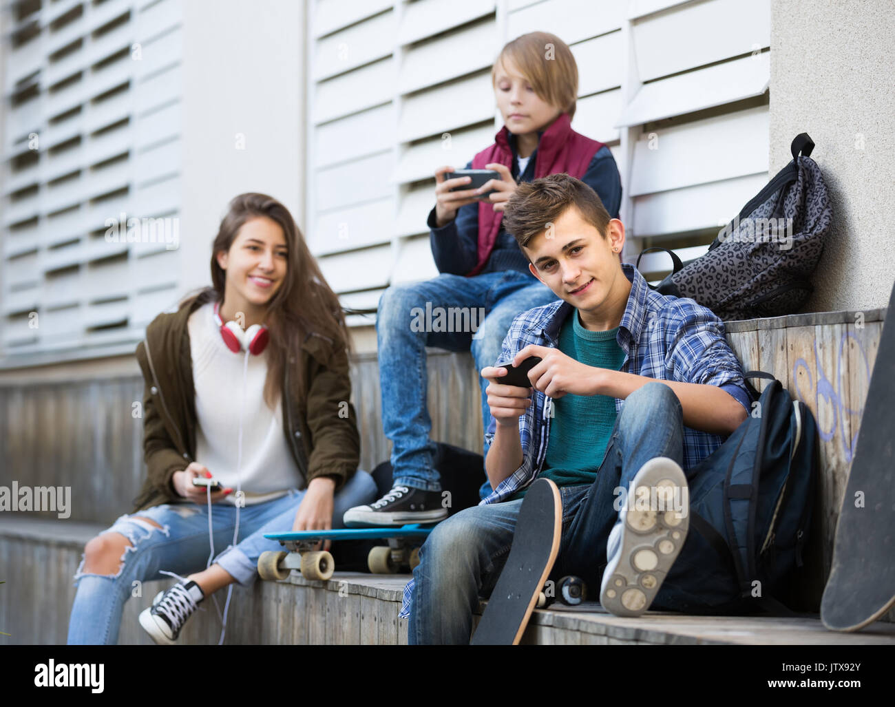 Three positive spanish teenagers with smartphones in autumn day