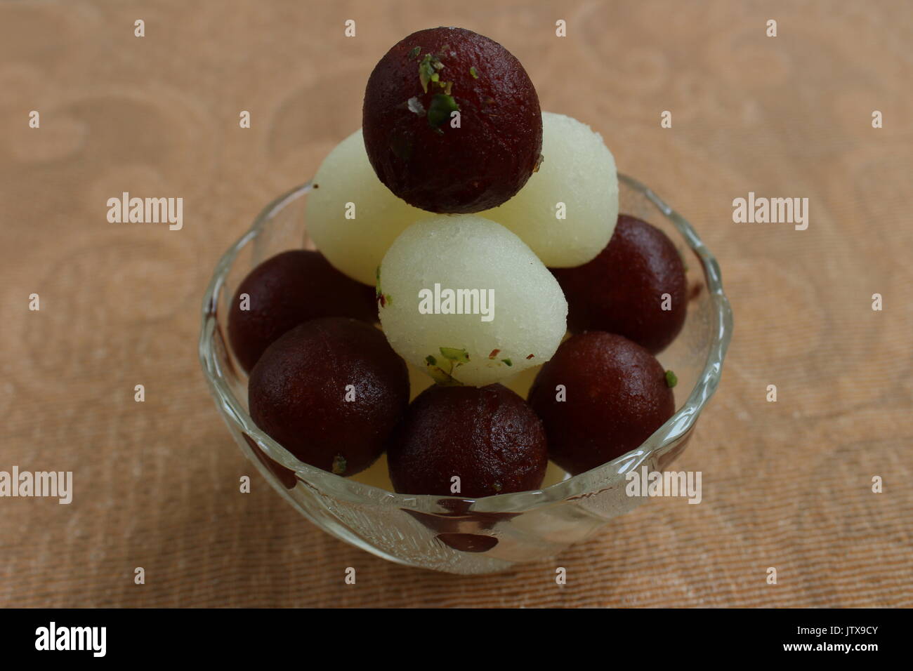 Gulab Jamun and Rasgulla lying one over another in a glass bowl Stock Photo
