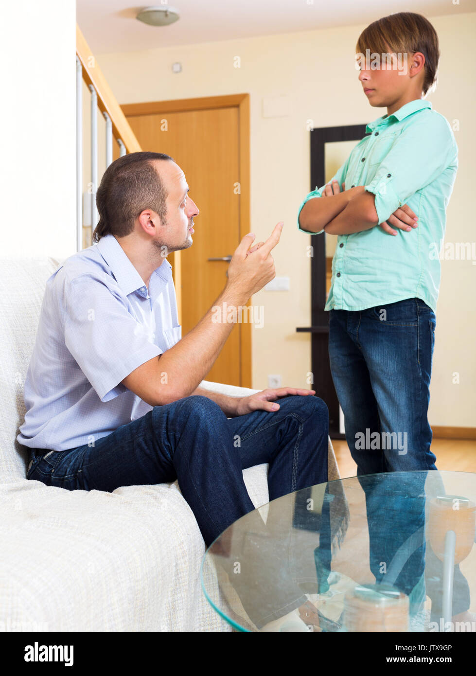 Riley father and teenage son discussing something interesting indoors. Focus on the man Stock Photo