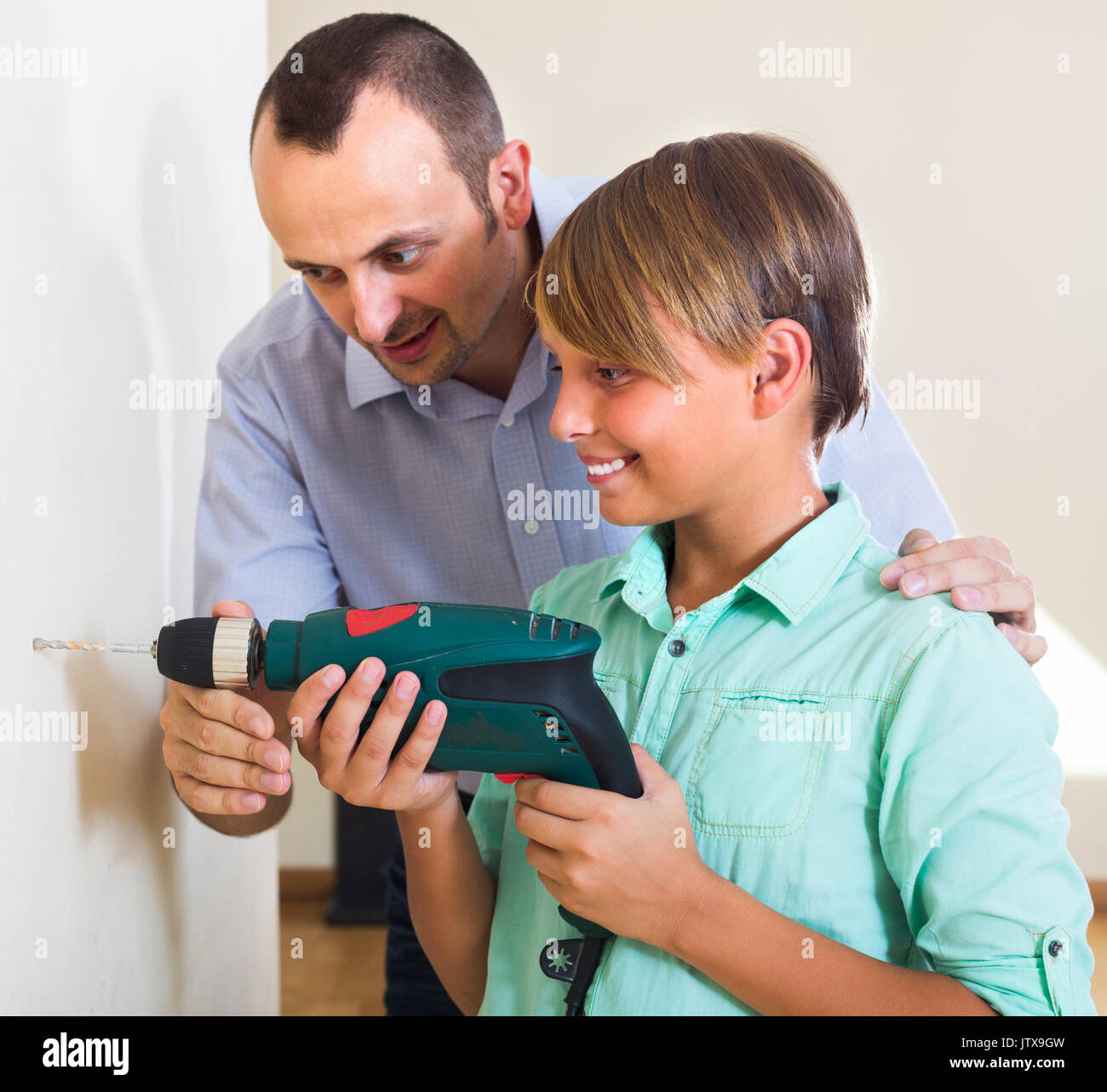 Happy man teaching son using electric drill at home Stock Photo