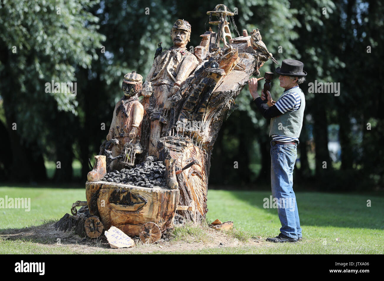 Boat Builder Tom Newstead, 70, from Seaton Sluice, with his carving of a mining scene which took him 3 months to complete, in a white willow which the council ordered to be cut down due to being unsafe, in Seat Deleval in Northumberland. Stock Photo
