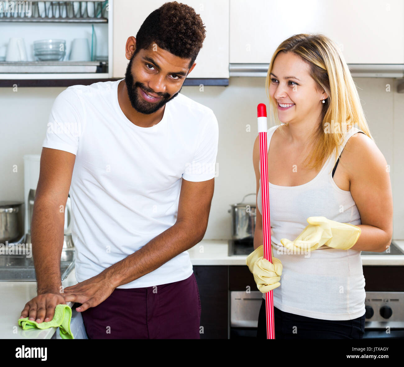 Black man with positive white woman dusting in domestic kitchen Stock ...