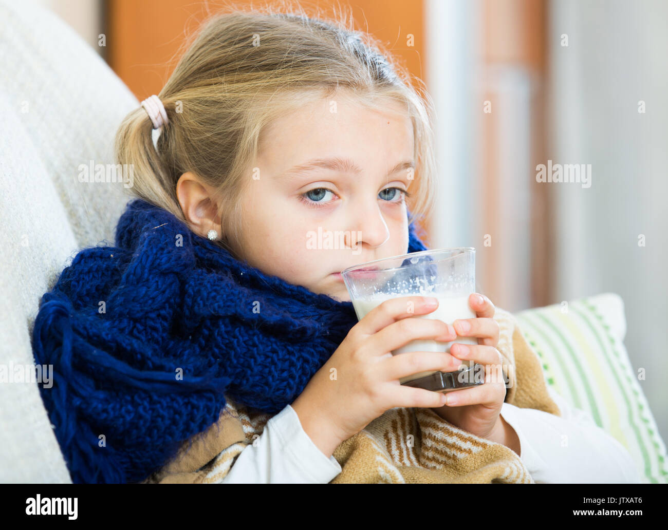 Little girl under blanket with warm milk and fever indoors Stock Photo