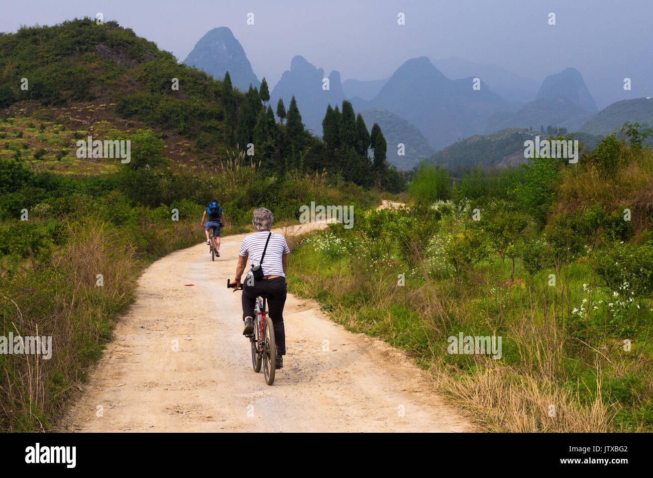 Tourists cycling in the rural countryside around XingPing, China Stock Photo