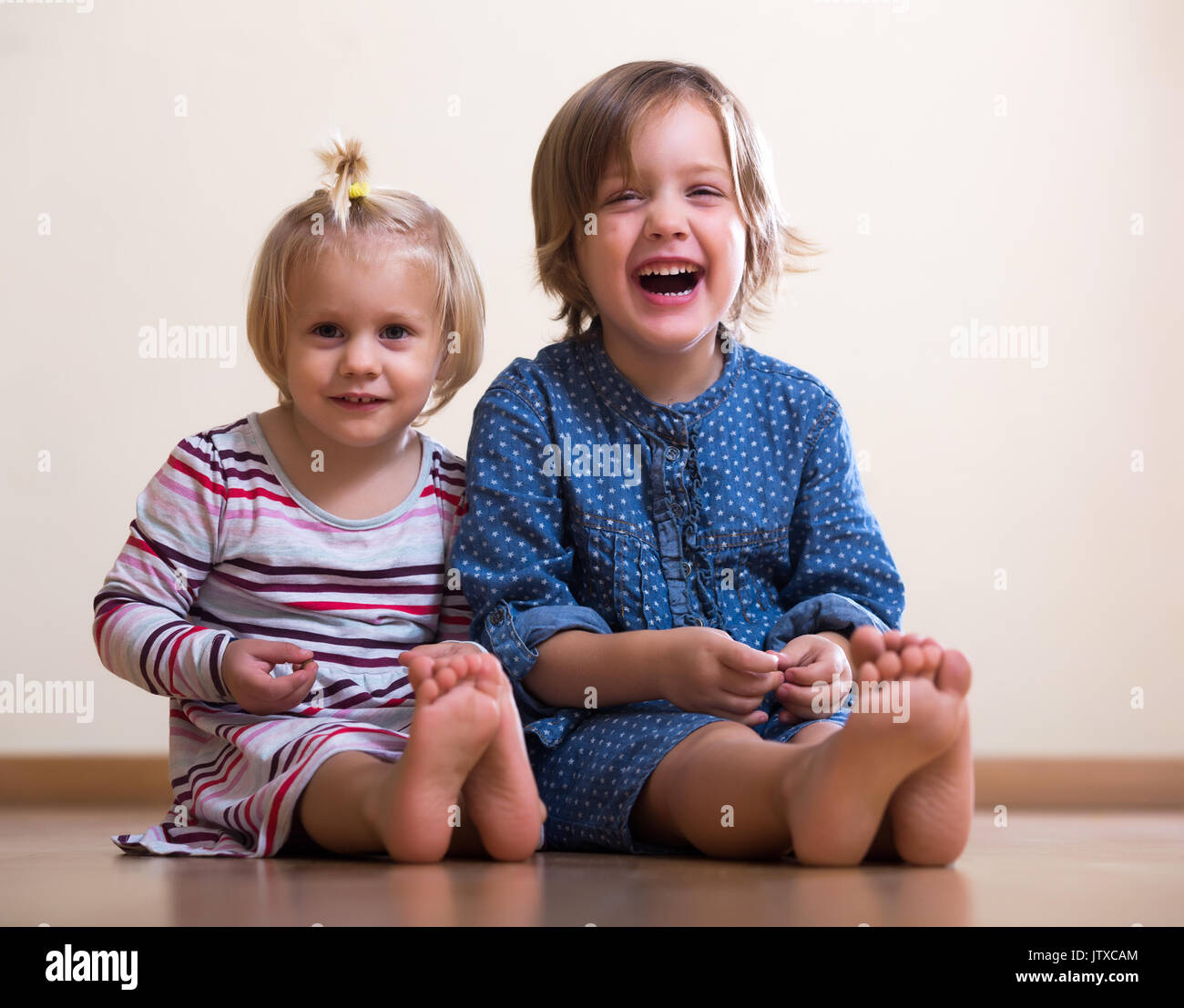 Two happy little girls sitting on the floor Stock Photo - Alamy