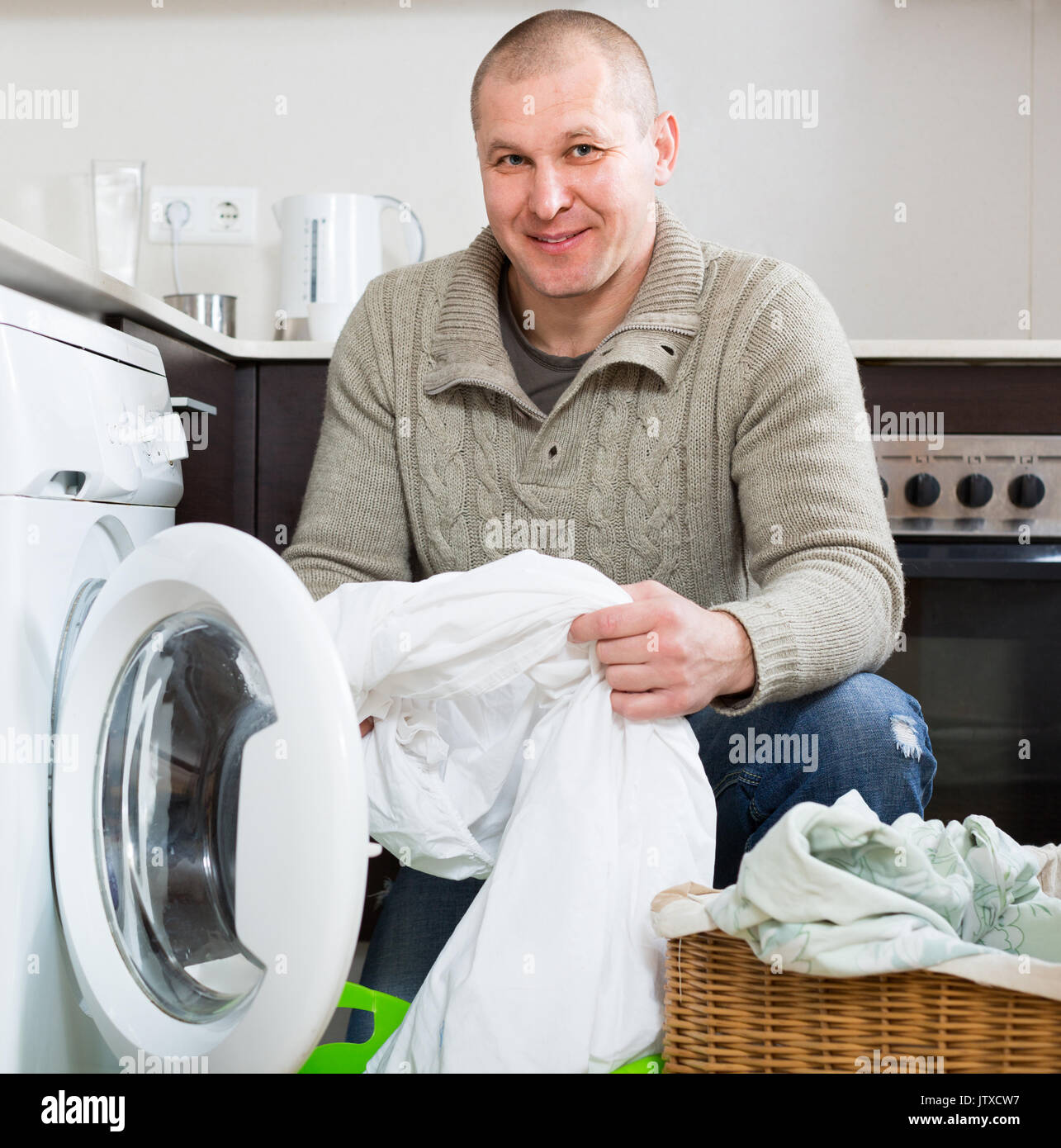 Home laundry. Happy smiling man using washing machine at home Stock Photo
