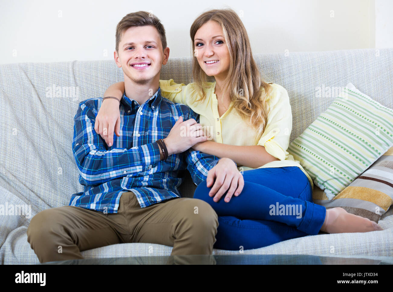 Young Spanish Guy And Pretty Girl Cuddling On Sofa Indoors Stock