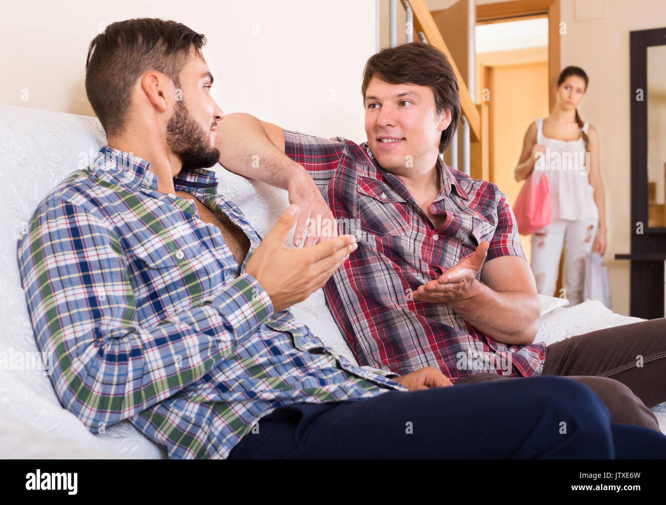 Wife watching partner having double talk with male friend Stock Photo