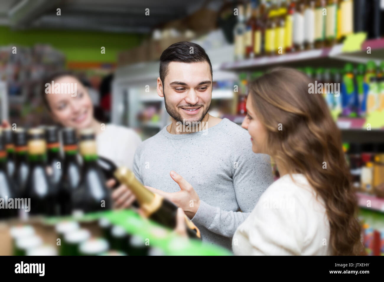 Adult happy shoppers choosing bottle of wine at liquor store Stock Photo