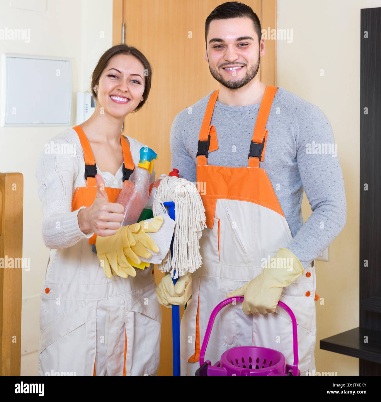 Portrait Of Professional Cleaners With Equipment At Door Of Client