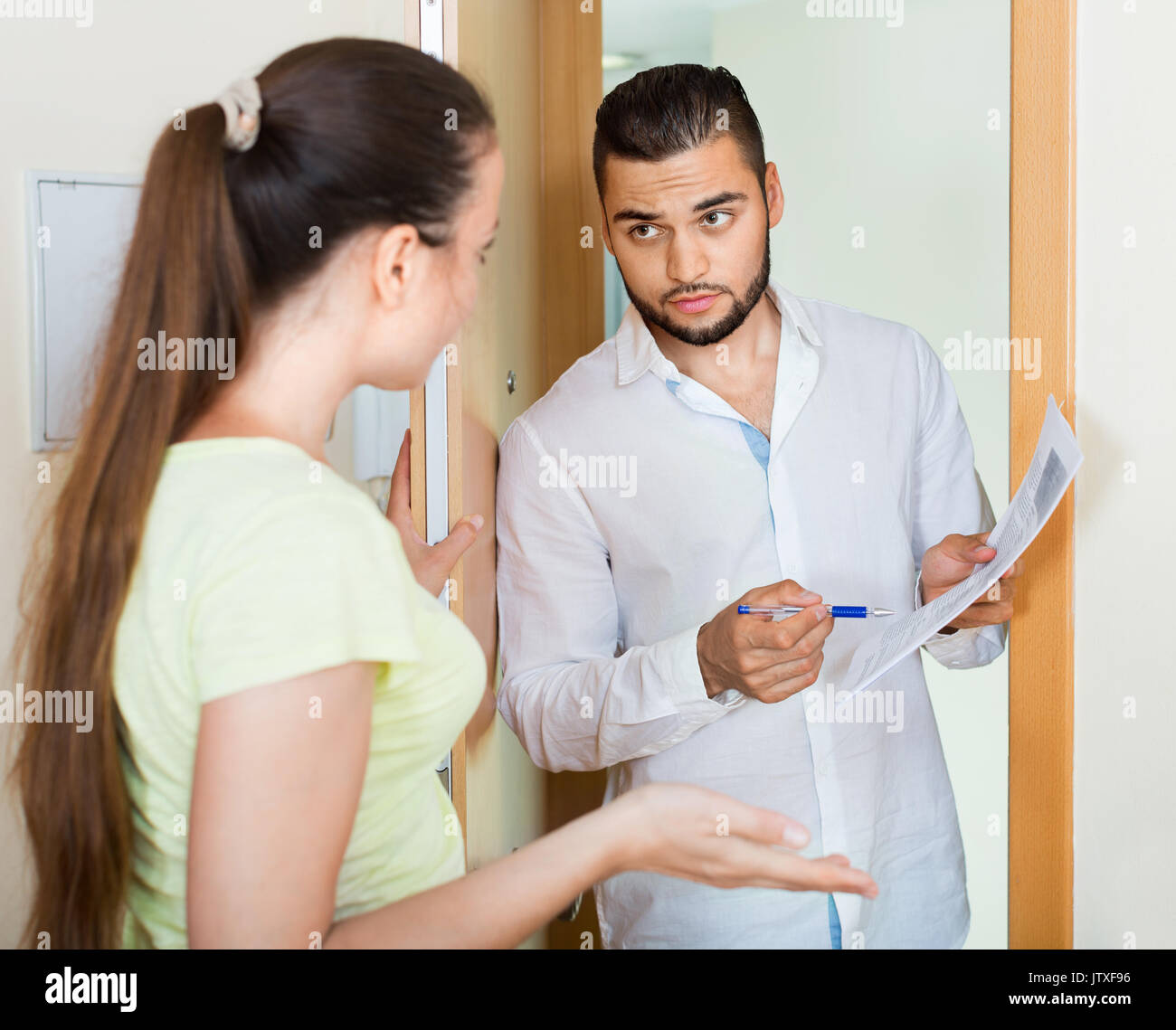 Businessman trying to collect money from housewife at door Stock Photo