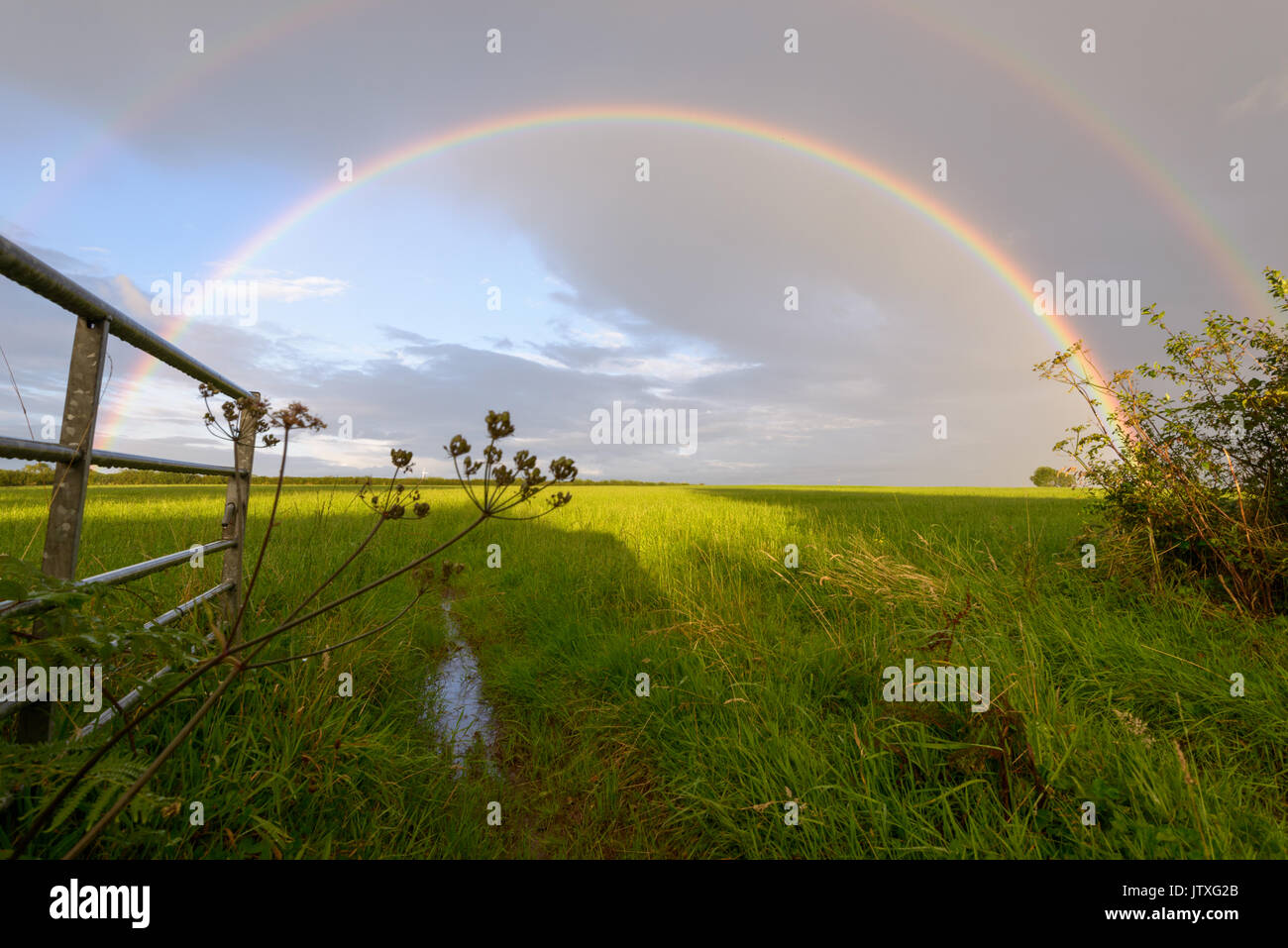Double rainbow against grey skies amid intermittent showers. Stock Photo