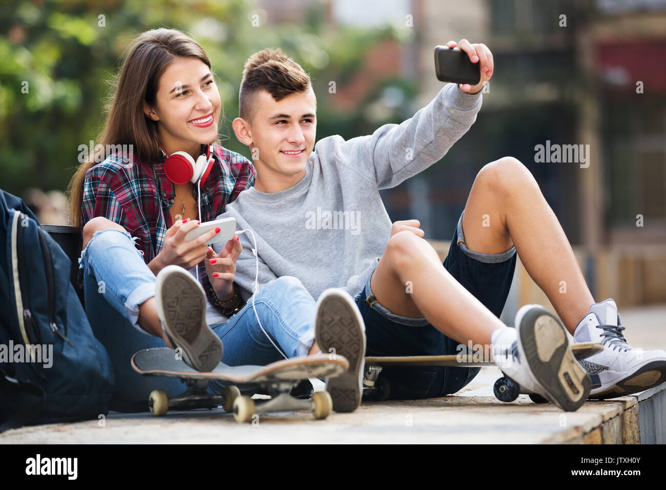 Smiling boy and girl teens posing at mobile phone for selfie Stock Photo